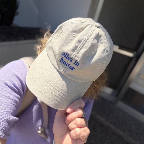 Beige Cap mit blauer „alles in butter“-Stickerei